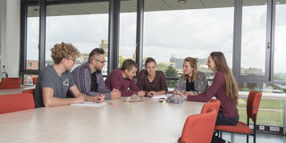 Studierende sitzen mit Lernunterlagen am Tisch.